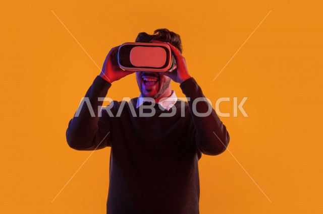 بورتريه رجل سعودي خليجي سعيد ،يضع جهازVR Box، ايماءات وجه و يدين تدل على السعادة و الاستمتاع ، استخدام تقنية ثلاثية الابعاد ، خلفية ملونة
