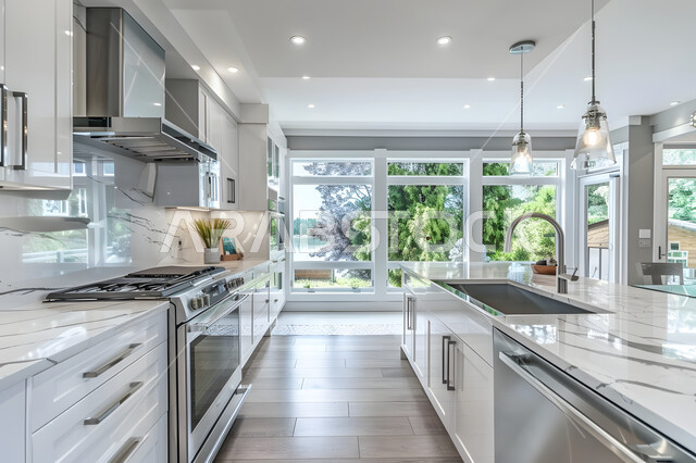 واجهة زجاجية مطلة على الطبيعة الخضراء داخل مطبخ أبيض أنيق، الديكورات الداخلية للشقق والفلل السكنية في المملكة العربية السعودية، تصاميم على الطراز المعماري الحديث