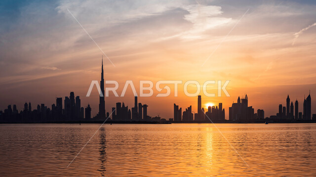 الواجهة البحرية على ساحل الخليج العربي، النمو والتقدم والتوسع العمراني، الفن الهندسي المعماري للمباني والمنشآت المطلة على البحر الإصطناعي، صورة ظليلية للأبراج وناطحات السحاب في دولة الإمارات العربية المتحدة في وقت غروب الشمس، معالم دبي السياحية