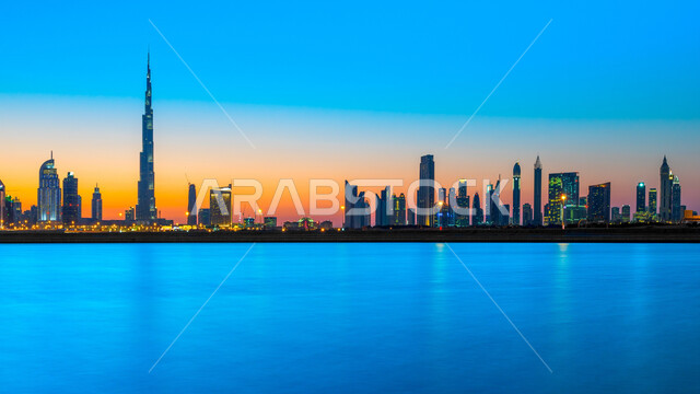 النمو والتقدم والتوسع العمراني، الفن الهندسي المعماري للمباني والمنشآت المطلة على البحر الإصطناعي، منظر الأبراج وناطحات السحاب في دولة الإمارات العربية المتحدة في وقت غروب الشمس، معالم دبي السياحية، الواجهة البحرية على ساحل الخليج العربي