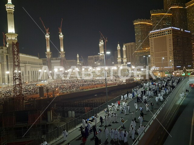 Visitors to the Sacred House of God gathered in the outer courtyard of the Sacred Mosque at night, Muslims from all over the world coming to the holy places in the Kingdom, famous Islamic religious monuments, worshipers entering the mosque to perform rituals and worship and get closer to God