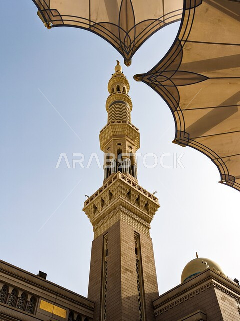 المظلات الالكترونية لجامع المدينة المنورة، صورة مقربة لمبنى مرتفع ملحق بالمسجد النبوي، العبادة والتقرب إلى الله، الفن الهندسي المعماري للمآذن والمساجد في المملكة العربية السعودية، منظر السماء الزرقاء