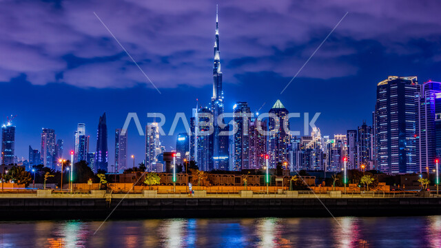 Architectural engineering art for buildings and facilities overlooking the sea, view of towers and skyscrapers in the United Arab Emirates at night, Dubai tourist attractions, waterfront on the Arabian Gulf coast, growth, progress and urban expansion