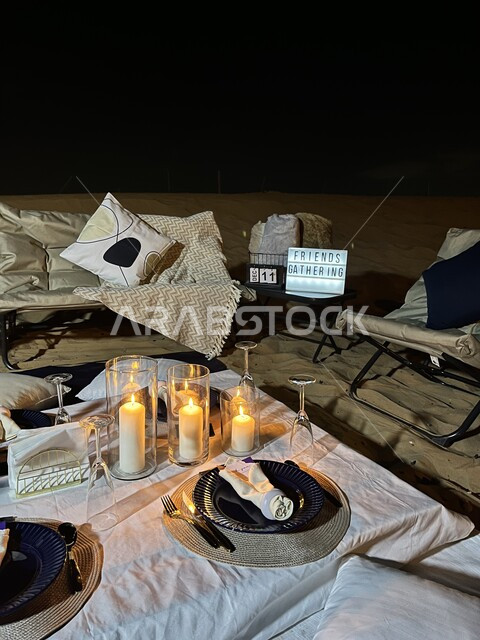 طاولة عشاء فاخرة مزينة بالشموع وسط الصحراء ، قضاء العطلة في براري المملكة العربية السعودية، الاستمتاع في الأجواء والجلسات الليلية الهادئة ، رحلة وكشتة برية في المناطق الصحراوية، الأماكن الترفيهية العائلية