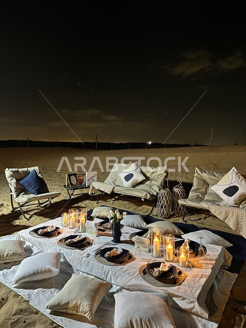 Spending vacation in the wilds of the Kingdom of Saudi Arabia, enjoying the atmosphere and quiet night sessions, a wild picnic trip in the desert areas, a luxurious dinner table decorated with candles in the middle of the desert, family entertainment places.