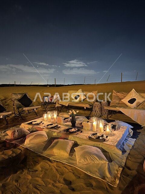 Enjoying the atmosphere and quiet night sessions, a wild trip and kashta in the desert areas, spending the holiday in the wilds of the Kingdom of Saudi Arabia, a luxurious dinner table decorated with candles in the middle of the desert, family entertainment places.