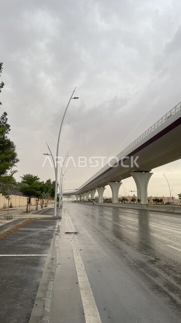التصميم الهندسي المعماري وزراعة الأشجار في طرق العاصمة، الأجواء الضبابية الغائمة في فصل الشتاء، الاماكن المخصصة للمشي والتجوال، الشوارع والطرقات الإسفلتيه المعبدة بعد هطول الأمطار، خط مترو مدينة الرياض في المملكة العربية السعودية