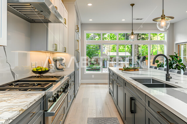 ديكور لمطبخ فاخر وراقي باللون الأبيض والأسود، واجهات ونوافذ زجاجية مطلة على الطبيعة، الشقق والفلل السكنية في المملكة العربية السعودية، التصميم الهندسي الكلاسيكي للمطابخ، أدوات منزلية حديثة بتقنيات عالية