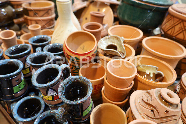المنتجات والأواني الفخارية المصنوعة من الطين ، متجر لبيع أواني الفخار في السوق الشعبي التقليدي في مدينة أبها في منطقة عسير، مهن وصناعات يدوية شعبية تراثية قديمة بالمملكة العربية السعودية، شراء الهدايا التذكارية والفخارات الملونة والمزخرفة