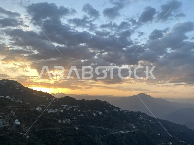 السماء المليئة بالغيوم وقت الغروب فوق جبال الفيفاء في جازان في المملكة العربية السعودية، اماكن ومعالم سياحية مشهورة جنوب السعودية، البيوت والمباني السكنية الاثرية، الاشجار والنباتات الخضراء، القمم والمرتفعات الجبلية