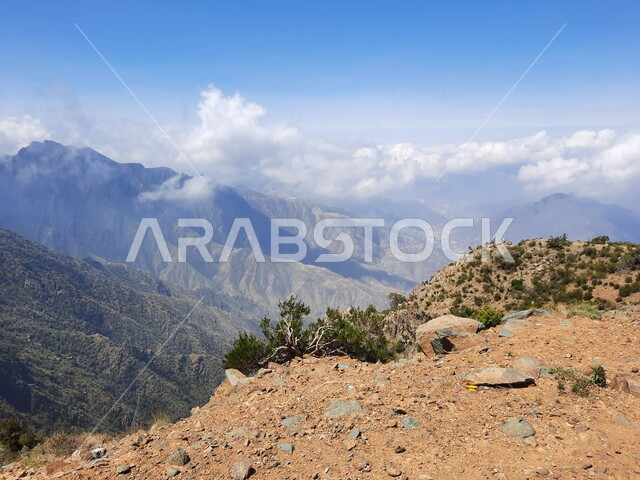 التكوينات والتشكيلات الجبلية الصخرية في مدينة ابها في المملكة العربية السعودية، مدن وأماكن سياحية طبيعية، نمو الأعشاب البرية والنباتات الخضراء في القمم والمرتفعات، منظر الغيوم البيضاء في اجواء فصل الصيف في عسير