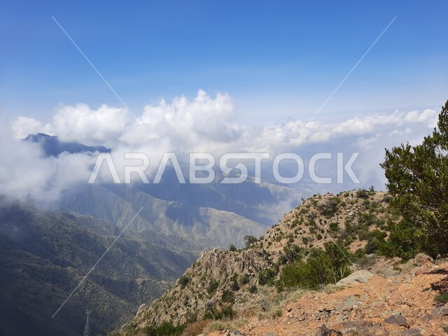 نمو الأعشاب البرية والنباتات الخضراء في القمم والمرتفعات، منظر الغيوم البيضاء في اجواء فصل الصيف في عسير، التشكيلات والتكوينات الجبلية الصخرية في مدينة ابها في المملكة العربية السعودية، مدن وأماكن سياحية طبيعية
