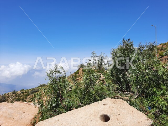 نمو الأعشاب البرية والنباتات الخضراء في القمم والمرتفعات، منظر الغيوم البيضاء في اجواء فصل الصيف في عسير، التشكيلات والتكوينات الجبلية الصخرية في مدينة ابها في المملكة العربية السعودية، مدن وأماكن سياحية طبيعية