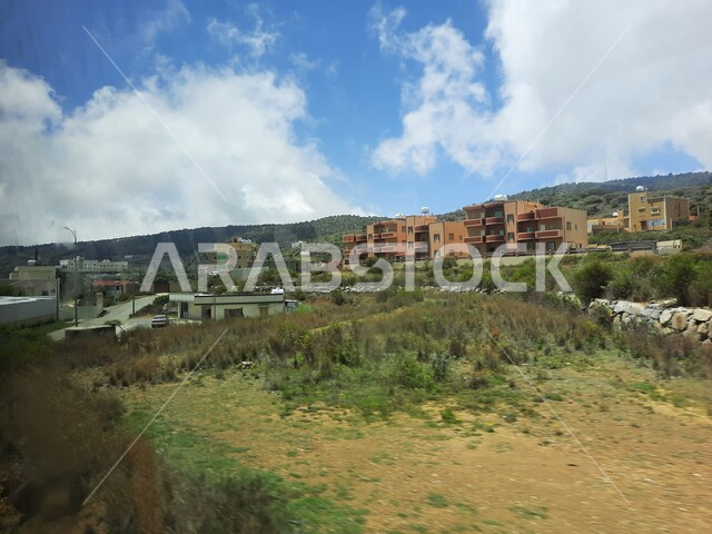 The view of clouds and white clouds in the sky, the mountain peaks and heights in the city of Abha, cities and natural tourist places in the Kingdom of Saudi Arabia, residential villages, homes and homes built on top of the mountain, agricultural fields and oases and green plants in the Asir Mountains.
