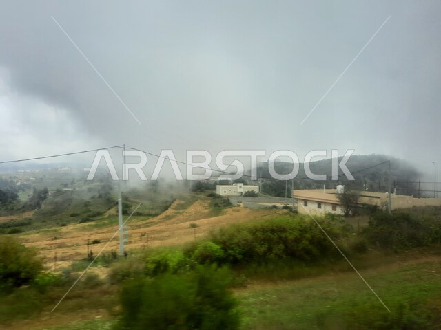 الواحات الزراعية والحقول والنباتات الخضراء في جبال عسير، منظر السحب والغيوم البيضاء في السماء، القمم والمرتفعات الجبلية في مدينة ابها، مدن وأماكن سياحية طبيعية في المملكة العربية السعودية، القرى السكنية والبيوت والمنازل المبنية أعلى الجبل