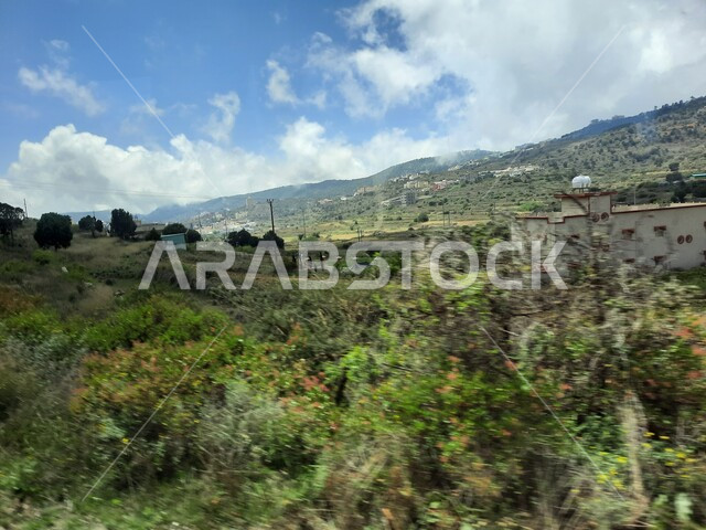 المدرجات الزراعية والحقول والنباتات الخضراء في جبال عسير، منظر السحب والغيوم البيضاء في السماء، القمم والمرتفعات الجبلية في مدينة ابها، مدن وأماكن سياحية طبيعية في المملكة العربية السعودية، القرى السكنية والبيوت والمنازل المبنية أعلى الجبل
