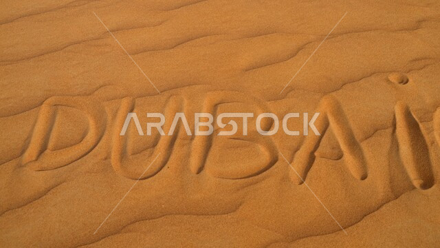 الكثبان الرملية في الصحاري، صورة مقربة لكلمة دبي باللغة الانجليزية على الرمال الذهبية الناعمة، مناطق البادية والبيئة الطبيعية الصحراوية في الإمارات العربية المتحدة، خلفيات الطبيعة