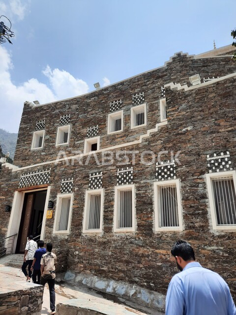 توافد السياح لزيارة الأماكن الأثرية، معالم سياحية مشهورة، الفن الهندسي المعماري للمباني على الطراز القديم، صورة مقربة لمبنى حجري مع نوافذ خشبية في قرية رجال ألمع التاريخي في منطقة عسير في المملكة العربية السعودية