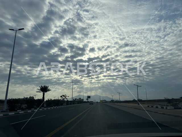 مشهد شروق الشمس في سماء السعودية، منظر الغيوم والسحب البيضاء المتجمعة فوق مدينة العيدابي شرق منطقة جازان، الطرق والشوارع الاسفلتية المعبدة، الاهتمام بالبنية التحتية في المدن والمناطق السياحية في المملكة