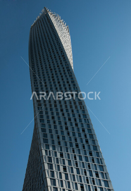 صورة من الأسفل لبرج كيان في مدينة دبي ، الفن الهندسي المعماري  للأبراج و ناطحات السحاب في الامارات العربيه المتحده، التصميم الملتوي  المتميز للبناء العملاق ، خلفيه زرقاء