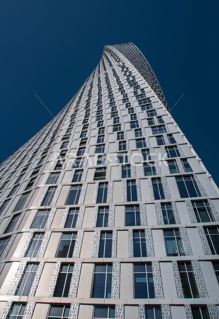 الفن الهندسي المعماري للأبراج و ناطحات السحاب في الامارات العربيه المتحده، صورة من الأسفل لبرج كيان في مدينة دبي ، التصميم الملتوي المتميز للبناء العملاق ، خلفيه زرقاء