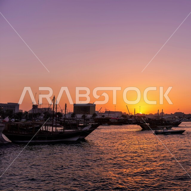 الواجهة البحرية في دولة قطر وقت غروب الشمس، أماكن سياحية لقضاء أوقات ممتعة، قارب خشبي وسط البحر على كورنيش مدينة الدوحة، الاستمتاع بالرحلات و النزهات البحرية الهادئة