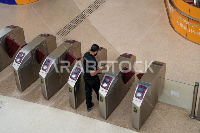 الأماكن والمعالم المشهورة، توفير وتأمين خدمات السفر والنقل في دولة قطر، موظف أمن يقوم بالدخول إلى محطة مترو مشيرب في مدينة الدوحة، المواصلات السريعة داخل حدود البلاد