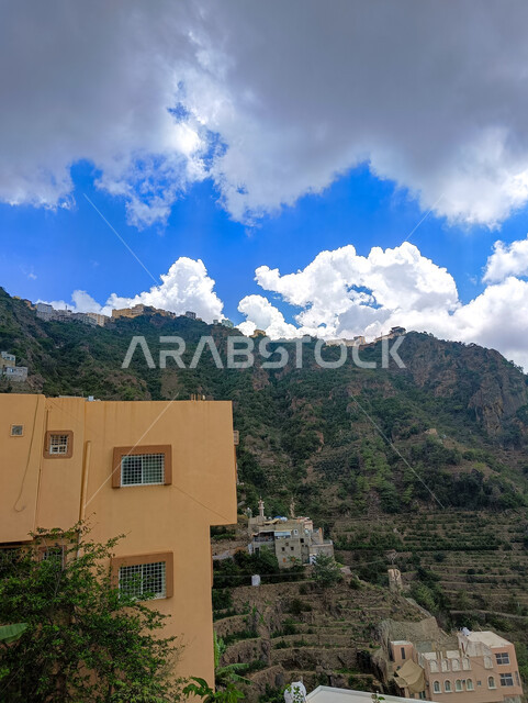  المدرجات الزراعية والبيوت والمباني السكنية في مدينة جازان، الأشجار والنباتات الخضراء المزروعة على سفوح الجبال, الاستمتاع بالمناظر الطبيعية في الأماكن السياحية في المملكة العربية السعودية، الغيوم والسحب البيضاء فوق القمم والمرتفعات الجبلية في محافظة فيفاء