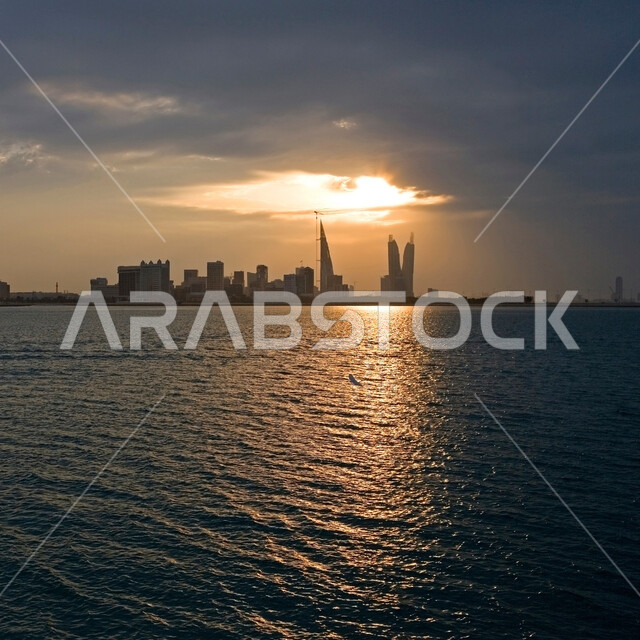الواجهة البحرية لمدينة المنامة في البحرين عند غروب الشمس، المناظر البحرية الهادئة، الأبراج والمباني وناطحات السحاب المضيئة المطلة على ساحل الخليج العربي، أماكن سياحية ترفيهية مشهورة في دولة البحرين