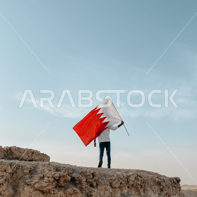 الاحتفال باليوم الوطني البحريني 16 ديسمبر، صورة من الخلف لشاب يقوم برفع علم مملكة البحرين سماء البلاد، أعلام الدول العربية، رموز وثقافات وطنية, حب الوطن والانتماء إليه، إحياء ذكرى استقلال الدولة 14 أغسطس