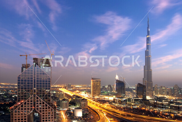 التقدم والتوسع العمراني في دولة الإمارات العربية المتحدة، الفن الهندسي المعماري للمباني والمنشآت السكنية والتجارية المضاءة في المساء، صورة جوية للأبراج وناطحات السحاب، برج خلفية في دبي