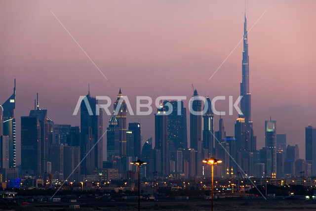 الفن الهندسي المعماري للمباني والمنشآت السكنية والتجارية المضاءة في المساء، التقدم والتوسع العمراني في دولة الإمارات العربية المتحدة، صورة جوية للأبراج وناطحات السحاب، برج خلفية في دبي