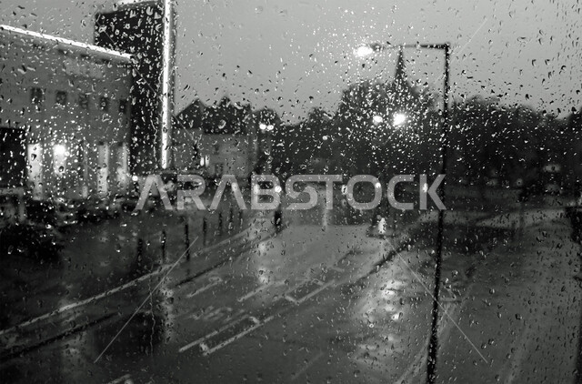 Rainy winter atmosphere, black and white image of water drops on a glass window, urban development of towers and skyscrapers in the United Arab Emirates, modern and advanced architectural engineering art for residential buildings
