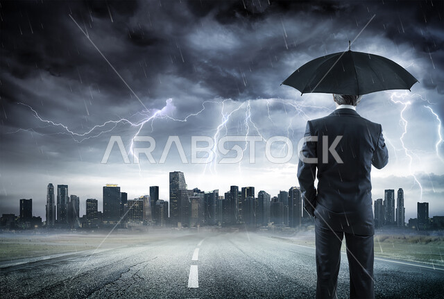 A view of thunder and lightning in the sky, historical tourist places and landmarks in the United Arab Emirates, the cold winter weather in Dubai, a night photo from behind of a man holding an umbrella to protect against the rain.