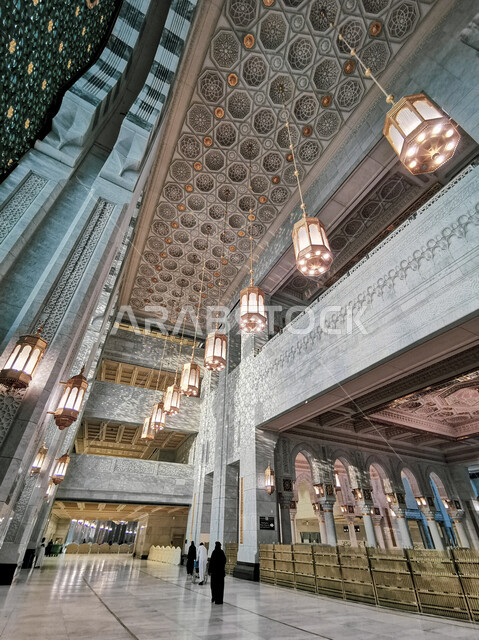 اماكن دينيه مقدسة, الزخارف الجبسيه الاسلاميه الفاخره على الأسقف، مجموعة من المسلمين يتجولون في ممرات توسعة الملك عبدالله للحرم المكي الشريف ,إدخال النجف على طراز الفوانيس العربيه والثريا في التصاميم المعماريه، صورة من داخل المسجد الحرام بمكة المكرمة في السعودية