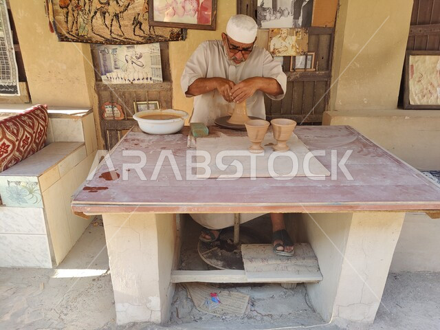 صنع أواني فخاريه شعبيه, رجل عربي خليجي سعودي يقوم بصناعة جرة فخار في سوق الاحساء الشعبي, تراثيات وشعبيات تقليدية, أوعية مزخرفه مصنوعه من الطين, حرف و صناعات يدوية سعوديه