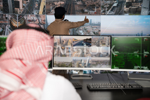 رجل سعودي خليجي يدير القسم الامني  ، يقوم بتتبع كاميرات المراقبة مع رجل الامن الذي يعمل بالمكان ،  ، يرتدي الزي السعودي التقليدي ، الحفاظ على الامن و الطمأنينة ، حراسة و امان 
