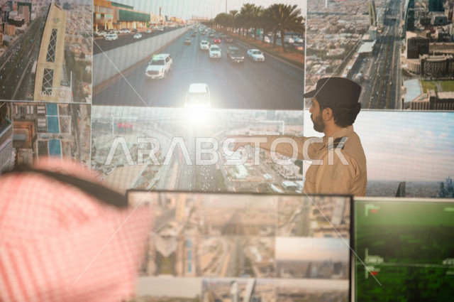 رجل سعودي خليجي يدير القسم الامني  ، يقوم بتتبع كاميرات المراقبة مع رجل الامن الذي يعمل بالمكان ،  ، يرتدي الزي السعودي التقليدي ، الحفاظ على الامن و الطمأنينة ، حراسة و امان 