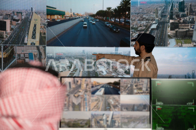 رجل سعودي خليجي يدير القسم الامني  ، يقوم بتتبع كاميرات المراقبة مع رجل الامن الذي يعمل بالمكان ،  ، يرتدي الزي السعودي التقليدي ، الحفاظ على الامن و الطمأنينة ، حراسة و امان 