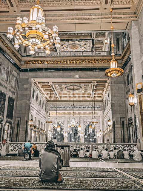 The Grand Mosque in Mecca from the inside in the Kingdom of Saudi Arabia, Islamic architectural art, the chandelier and hanging lights in the Holy Mosque of Mecca, the arts and decorations of Islamic architecture, a picture from the back of a Saudi Gulf Arab man wearing the traditional dress performing the obligatory prayer