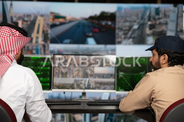 رجل سعودي خليجي يدير القسم الامني  ، يقوم بتتبع كاميرات المراقبة مع رجل الامن الذي يعمل بالمكان ،  ، يرتدي الزي السعودي التقليدي ، الحفاظ على الامن و الطمأنينة ، حراسة و امان 