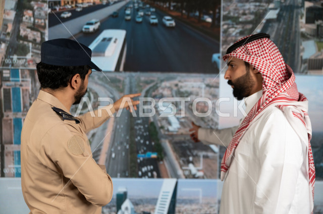 رجل سعودي خليجي يدير القسم الامني  ، يقوم بتتبع كاميرات المراقبة مع رجل الامن الذي يعمل بالمكان ،  ، يرتدي الزي السعودي التقليدي ، الحفاظ على الامن و الطمأنينة ، حراسة و امان 