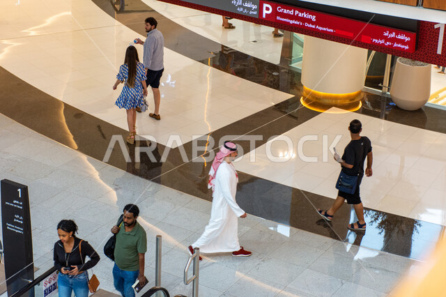 صورة من أعلى لمجموعة من السياح داخل دبي مول بإمارة دبي، السياحة في الإمارات العربية المتحدة، مراكز التسوق والمتاجر الفاخرة، اماكن الأنشطة العائلية الترفيهية، الفن الهندسي والتصاميم والديكورات الداخلية للمولات