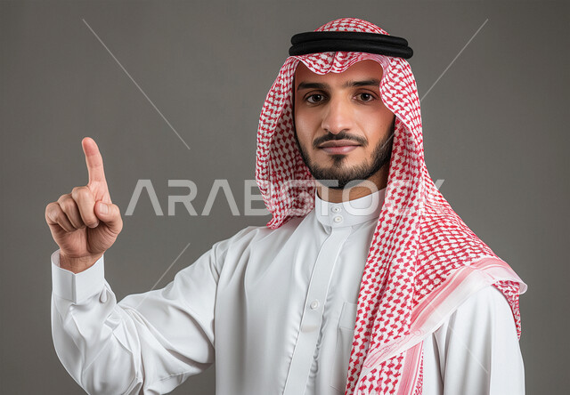 حركات وايماءات وجه ويدين مختلفة، الاشارة الى شيء ما، بورتريه مقرب لرجل عربي خليجي سعودي يرتدي الشماغ والثوب التقليدي يرفع اصبعه للأعلى، خلفية رمادية