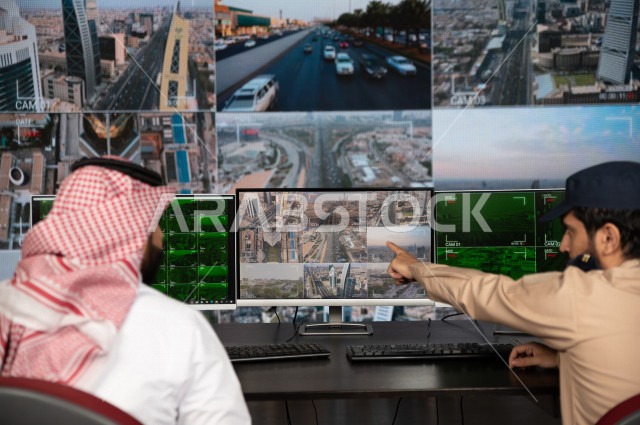 رجل سعودي خليجي يدير القسم الامني  ، يقوم بتتبع كاميرات المراقبة مع رجل الامن الذي يعمل بالمكان ،  ، يرتدي الزي السعودي التقليدي ، الحفاظ على الامن و الطمأنينة ، حراسة و امان 