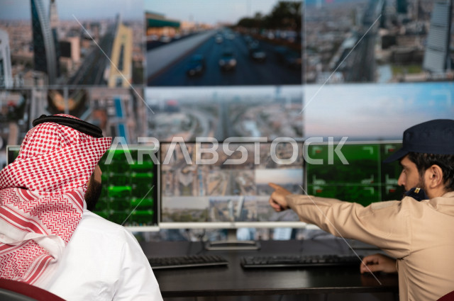 رجل سعودي خليجي يدير القسم الامني  ، يقوم بتتبع كاميرات المراقبة مع رجل الامن الذي يعمل بالمكان ،  ، يرتدي الزي السعودي التقليدي ، الحفاظ على الامن و الطمأنينة ، حراسة و امان 