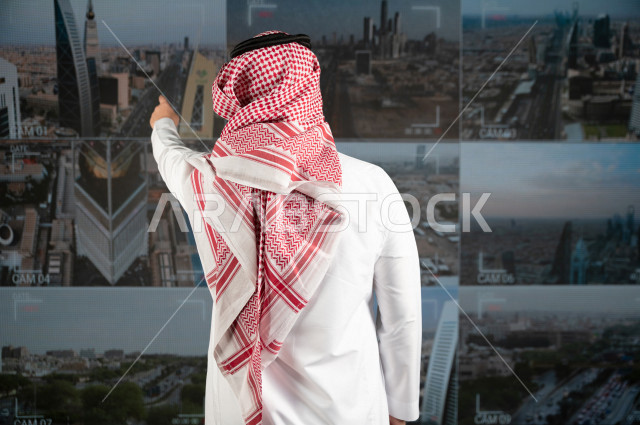 رجل سعودي خليجي يدير القسم الامني  ، يقوم بتتبع كاميرات المراقبة  ، يرتدي الزي السعودي التقليدي ، الحفاظ على الامن و الطمأنينة ، حراسة و امان 