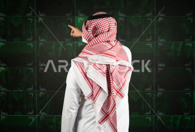 رجل سعودي خليجي يدير القسم الامني  ، يقوم بتتبع كاميرات المراقبة  ، يرتدي الزي السعودي التقليدي ، الحفاظ على الامن و الطمأنينة ، حراسة و امان 