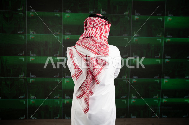 رجل سعودي خليجي يدير القسم الامني  ، يقوم بتتبع كاميرات المراقبة  ، يرتدي الزي السعودي التقليدي ، الحفاظ على الامن و الطمأنينة ، حراسة و امان 