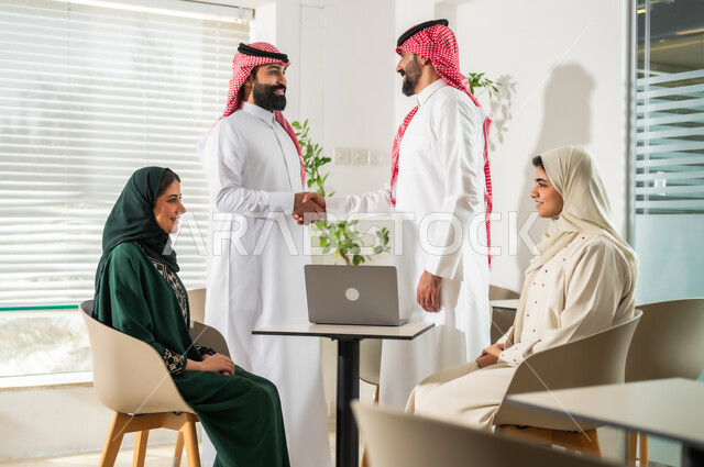 Cooperation and understanding among colleagues to achieve the company’s goals, a business meeting between Saudi Gulf Arab employees in the meeting room, dialogues and discussions to achieve strategies and goals, a comfortable work environment in Saudi companies, the use of modern technical devices in offices.